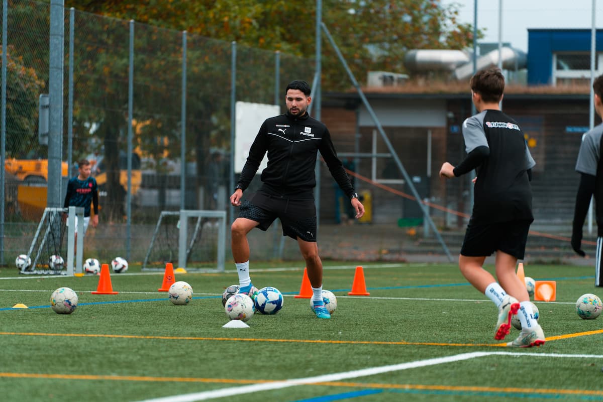 Fussballtrainer leitet Techniktraining mit jungen Spielern auf dem Platz.